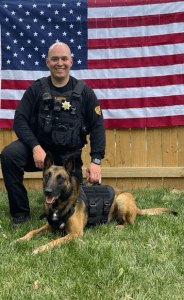 K9 laying down in front of a flag